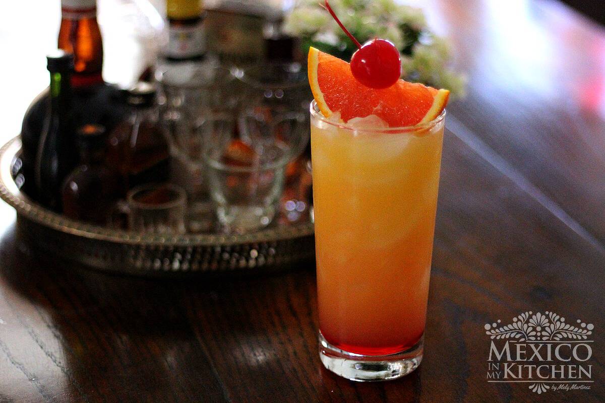 Tequila sunrise cocktail topped with a maraschino cherry and orange slice