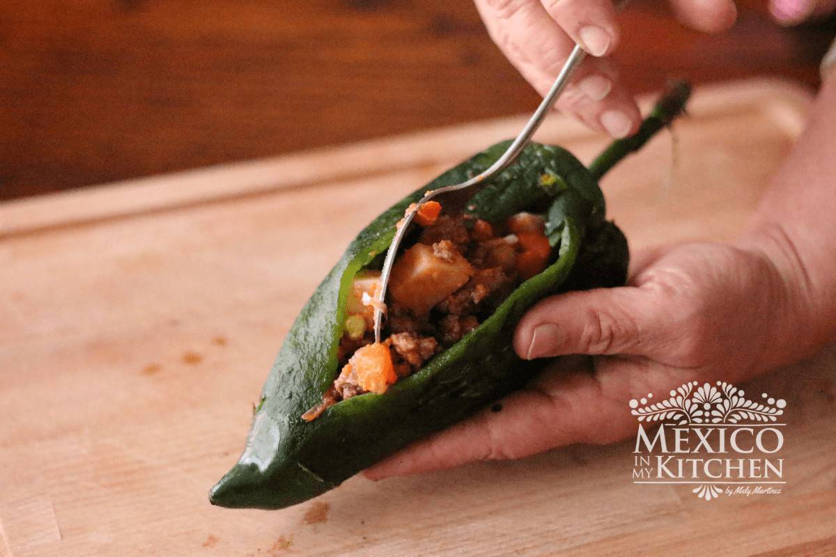 Chiles poblanos being stuffed with picadillo.