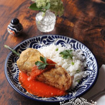 Chiles rellenos served with red salsa and white rice