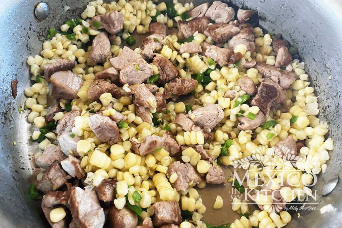 Searing meat, corn and zucchini on a frying pan