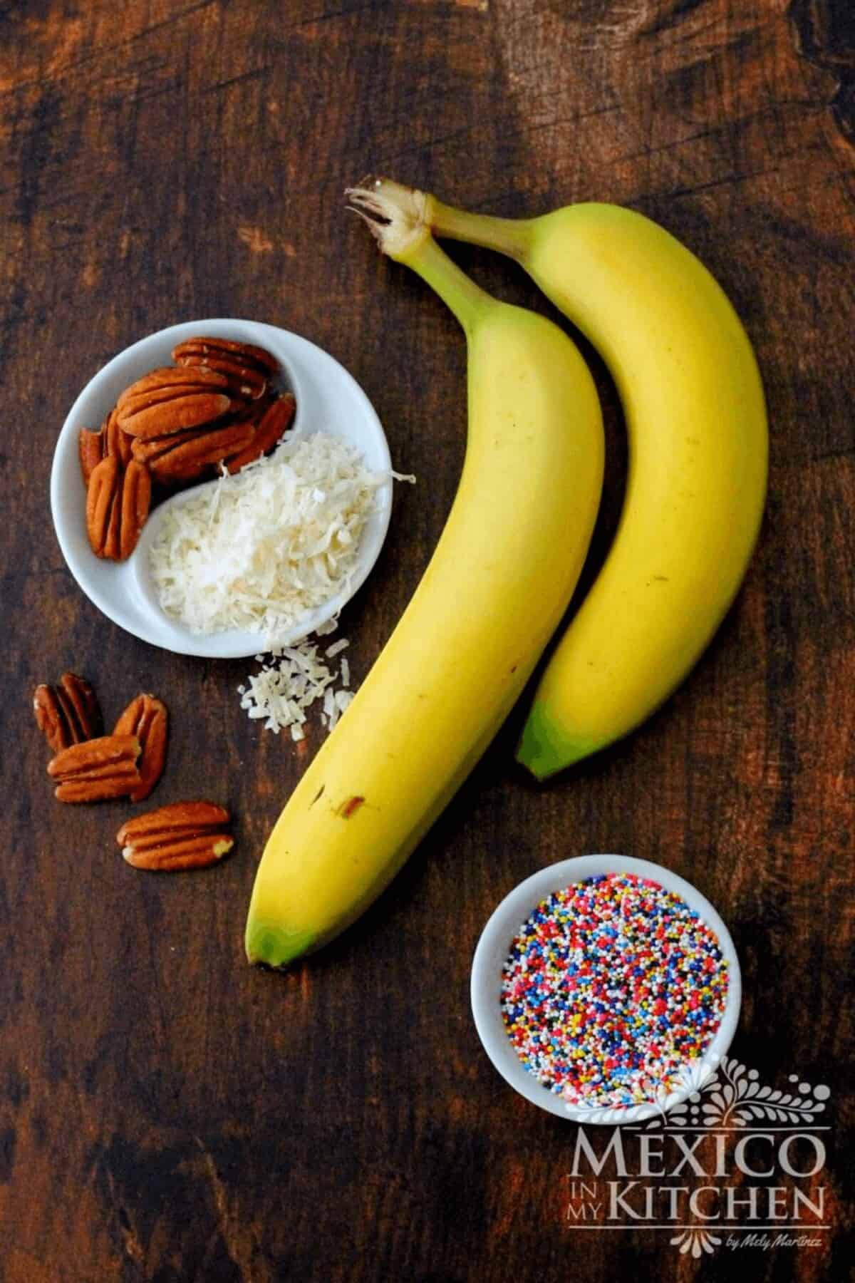 Bananas, sprinkles, shredded coconut and nuts on a table.