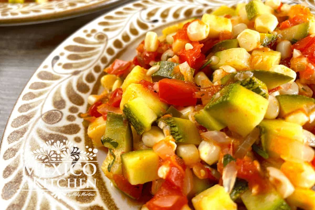Closeup of Mexican Zucchini, corn, and tomato (calabacitas con elote) served on a plate.