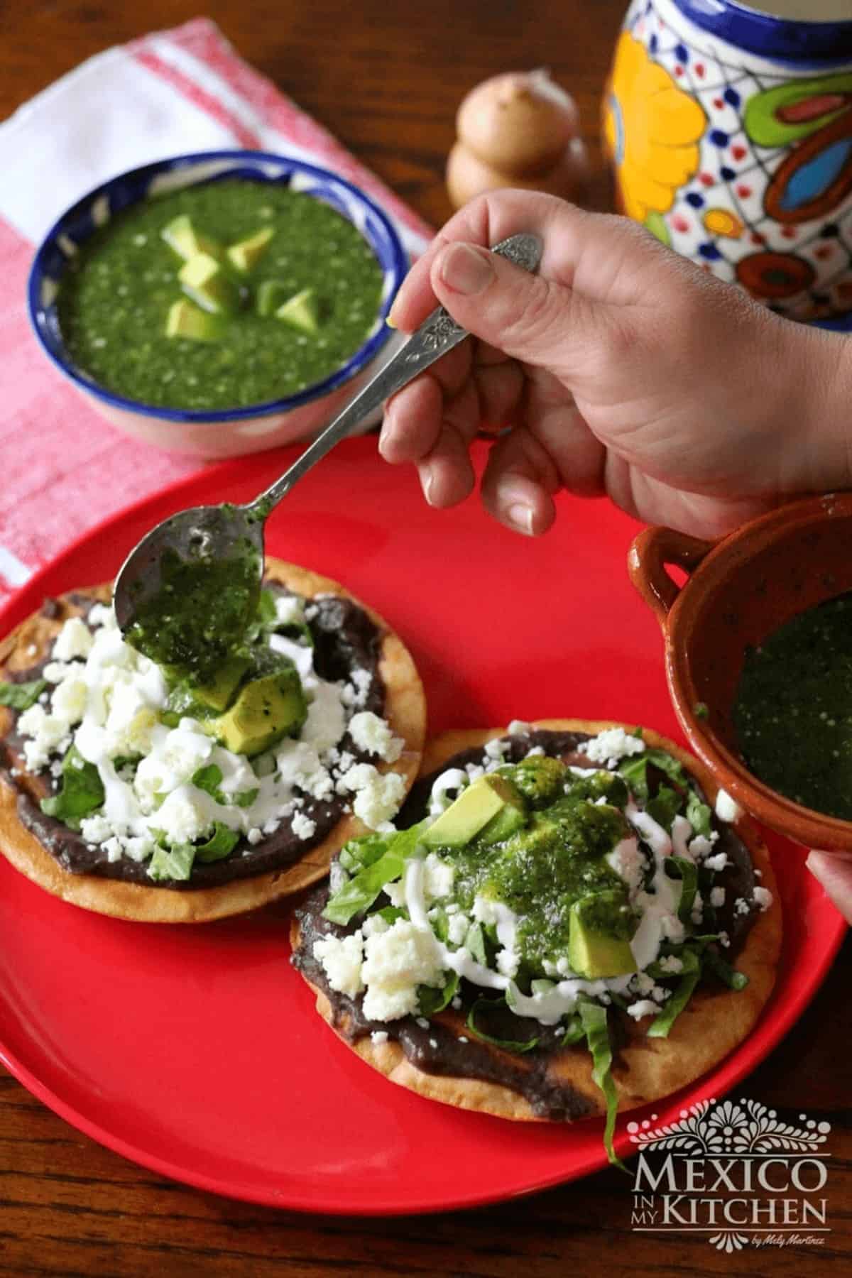 Two bean tostadas with avocado, cheese, crema and topped with salsa.