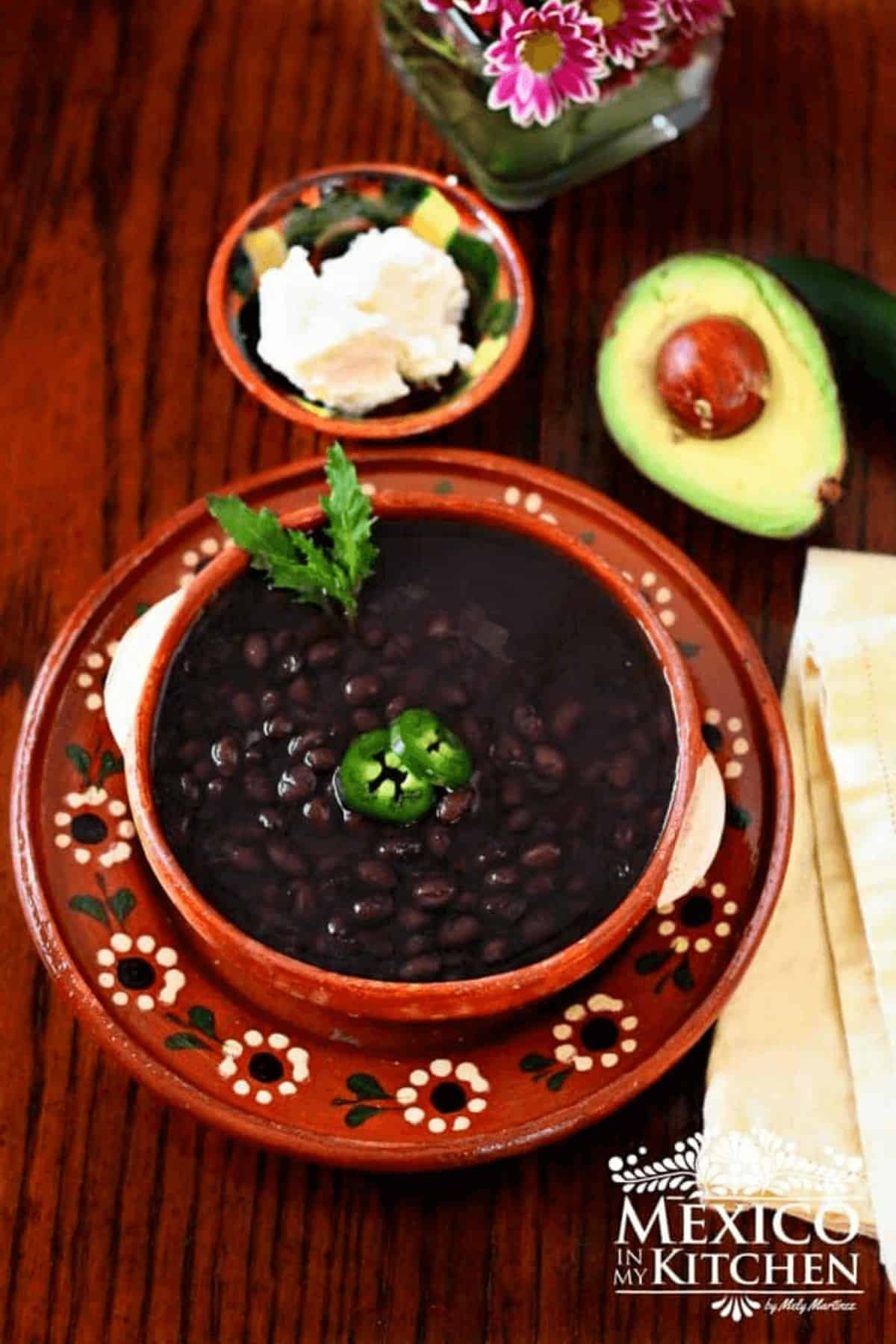 Black beans served in a bowl topped with jalapeños.