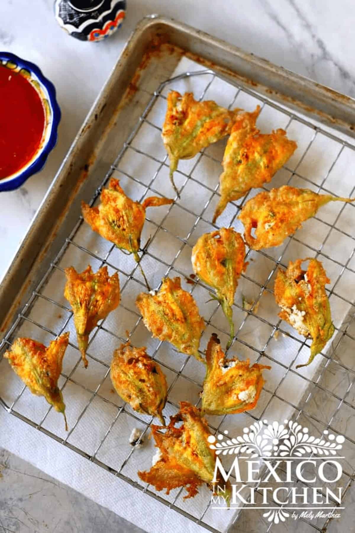 Fried and stuffed squash flowers on a wire rack