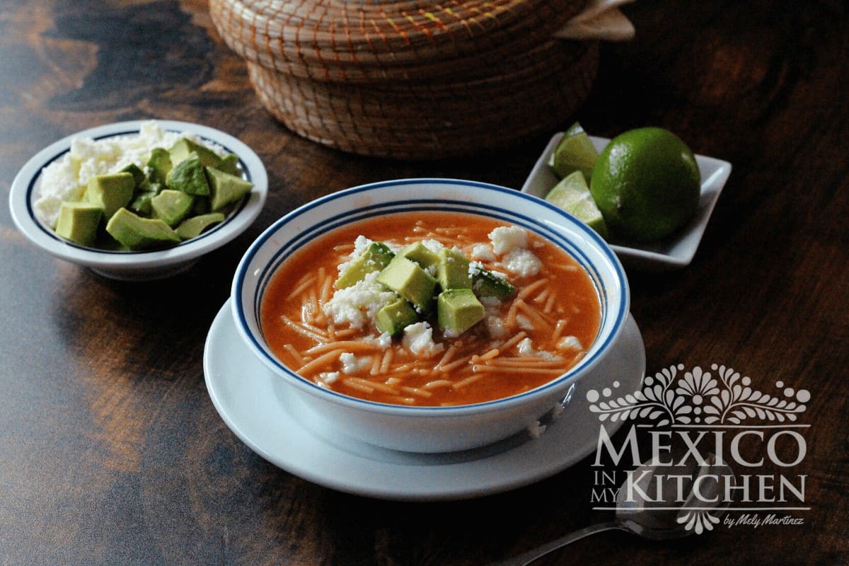 Sopa de fideo served in a bowl, topped with queso fresco and avocado.