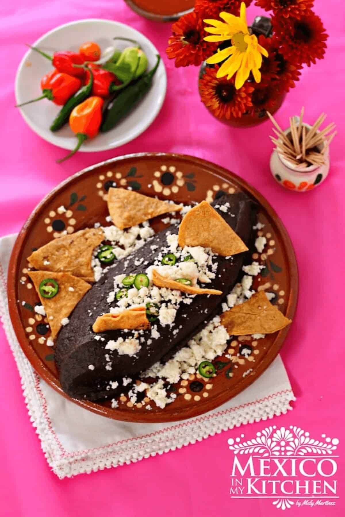 Frijoles refritos (Black refried beans) topped with jalapeños, queso fresco and tortilla chips.