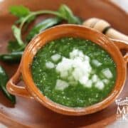 Green salsa verde served in a bowl, topped with white onions.