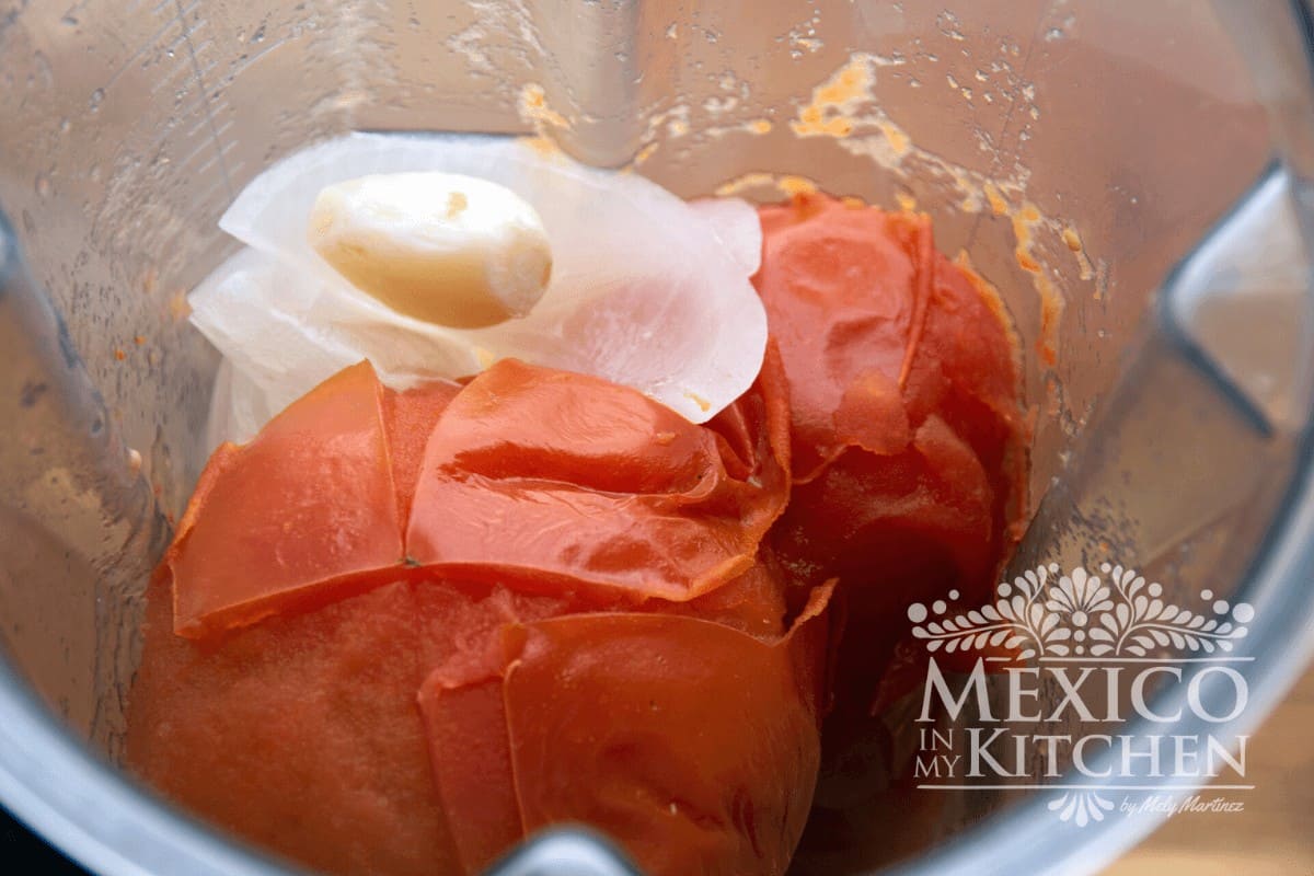 Tomatoes, onions, and garlic in a blender to make Mexican tomato sauce. 