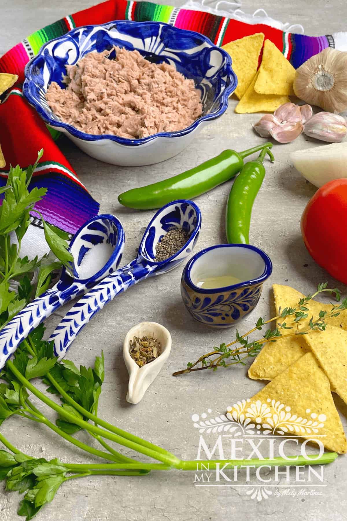 Display of ingredients like canned tuna, serrano peppers, parsley, garlic and spices.