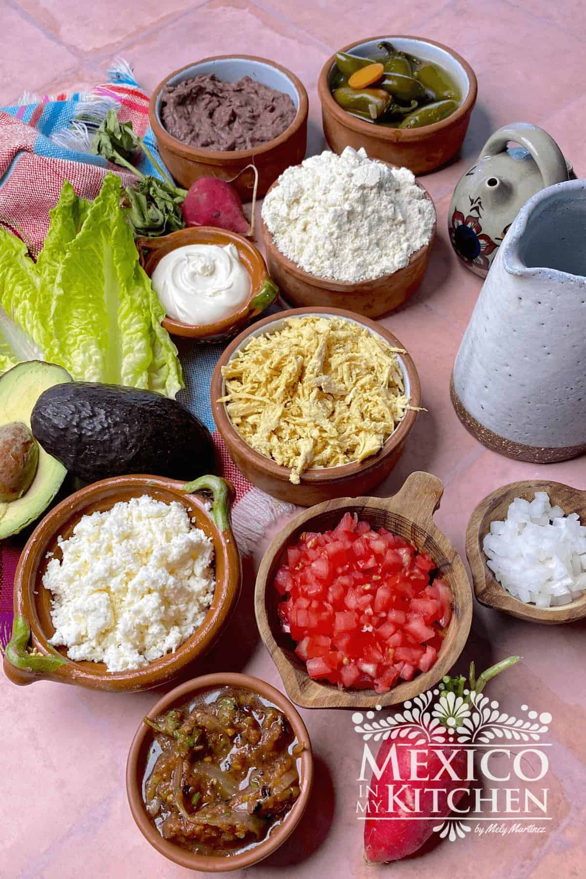 Ingredients for Mexican Sopes like masa harina, beans, chicken, queso fresco, tomatoes, and lettuce.