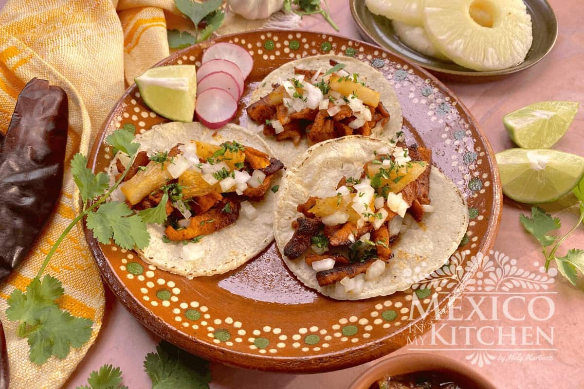 Tacos al pastor topped with white onions, pineapple and fresh cilantro.
