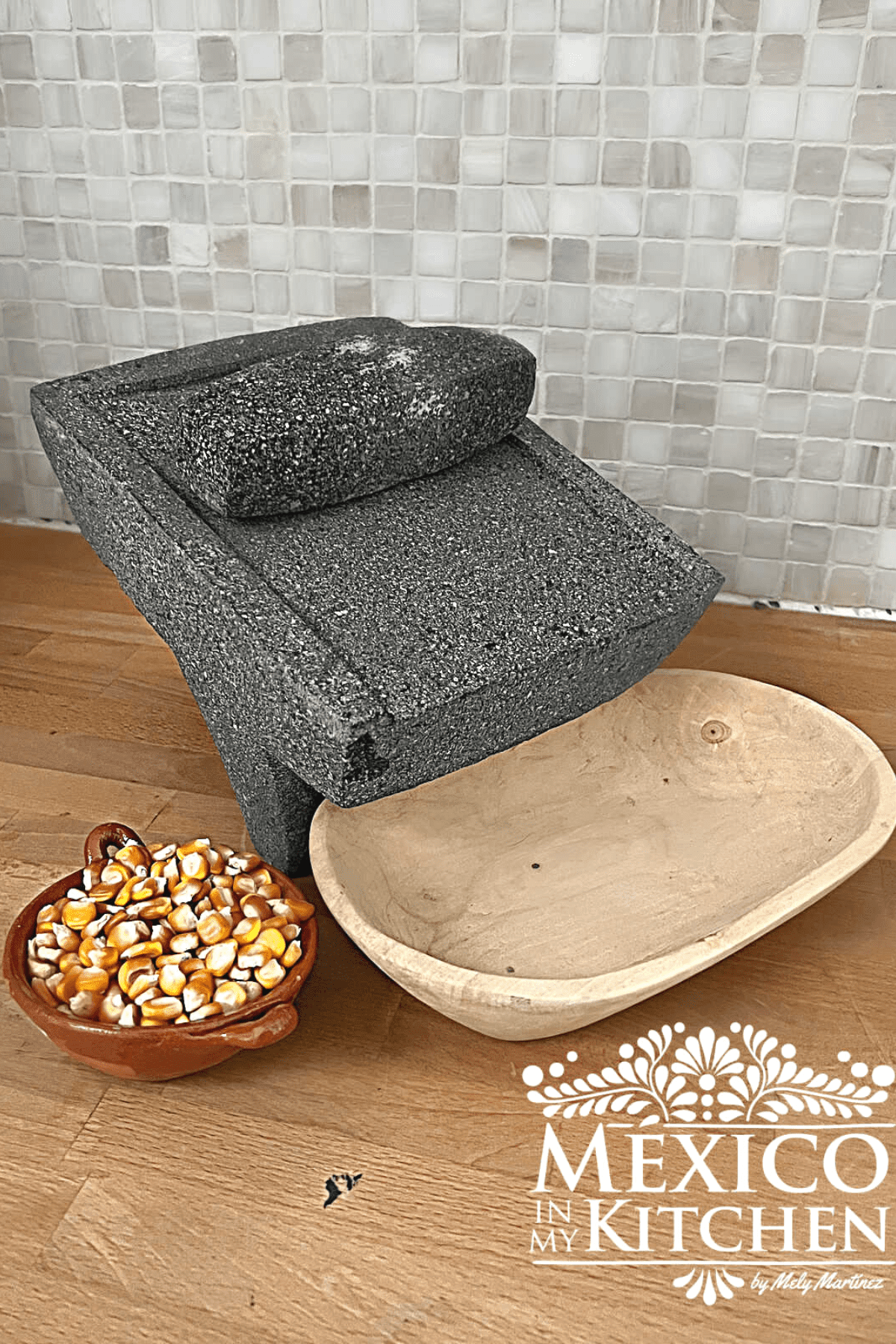 Mexican Metate with a wooden bowl next to a clay bowl full of corn.