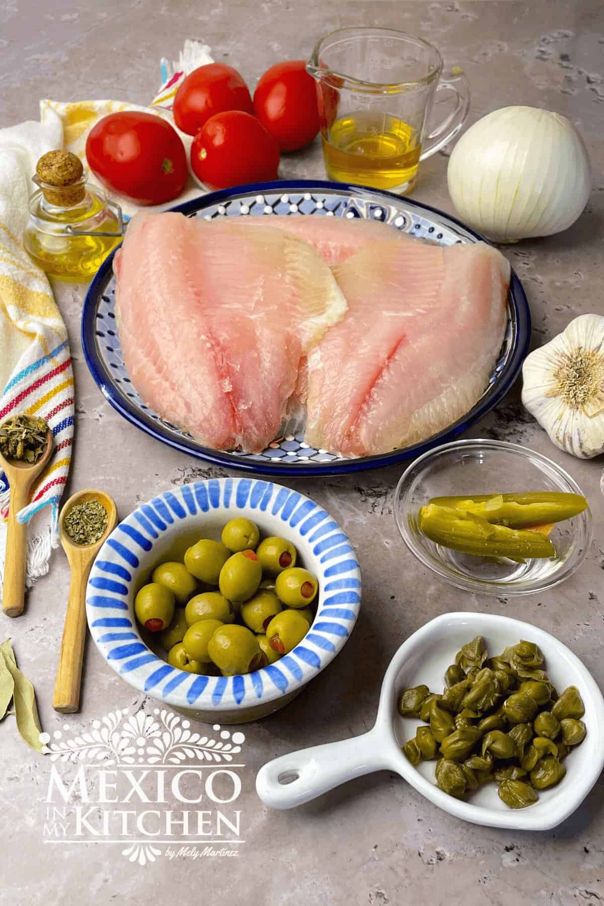 Ingredients for Tilapia Veracruz Style like white fish fillets, capers, olives, onions, tomatoes and herbs.