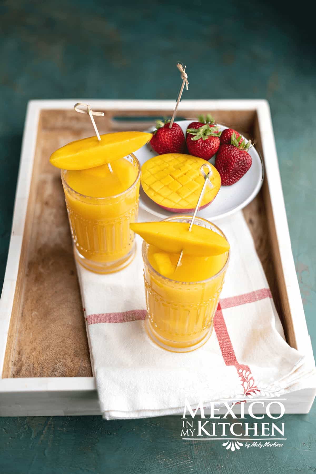 Mango agua fresca in glasses topped with mango slices.