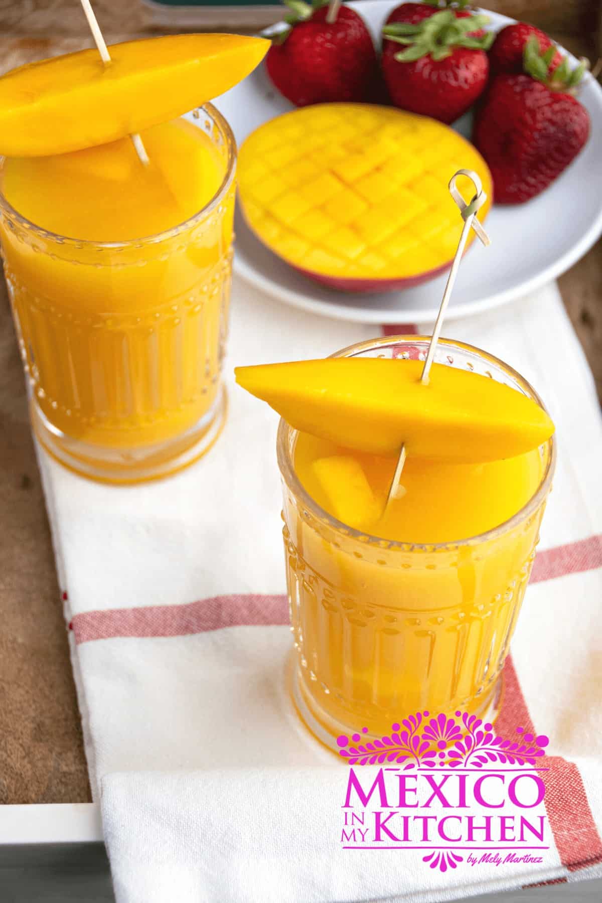 Mango agua fresca in glasses topped with mango slices.