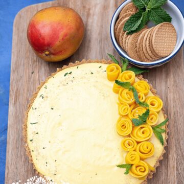 No bake mango pie served on a cutting board, and topped with mango shape flowers.