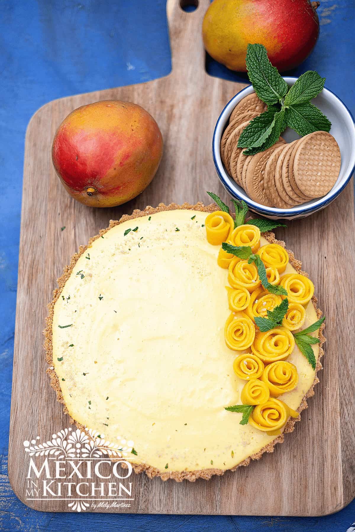 No bake mango pie served on a cutting board, and topped with mango shape flowers.