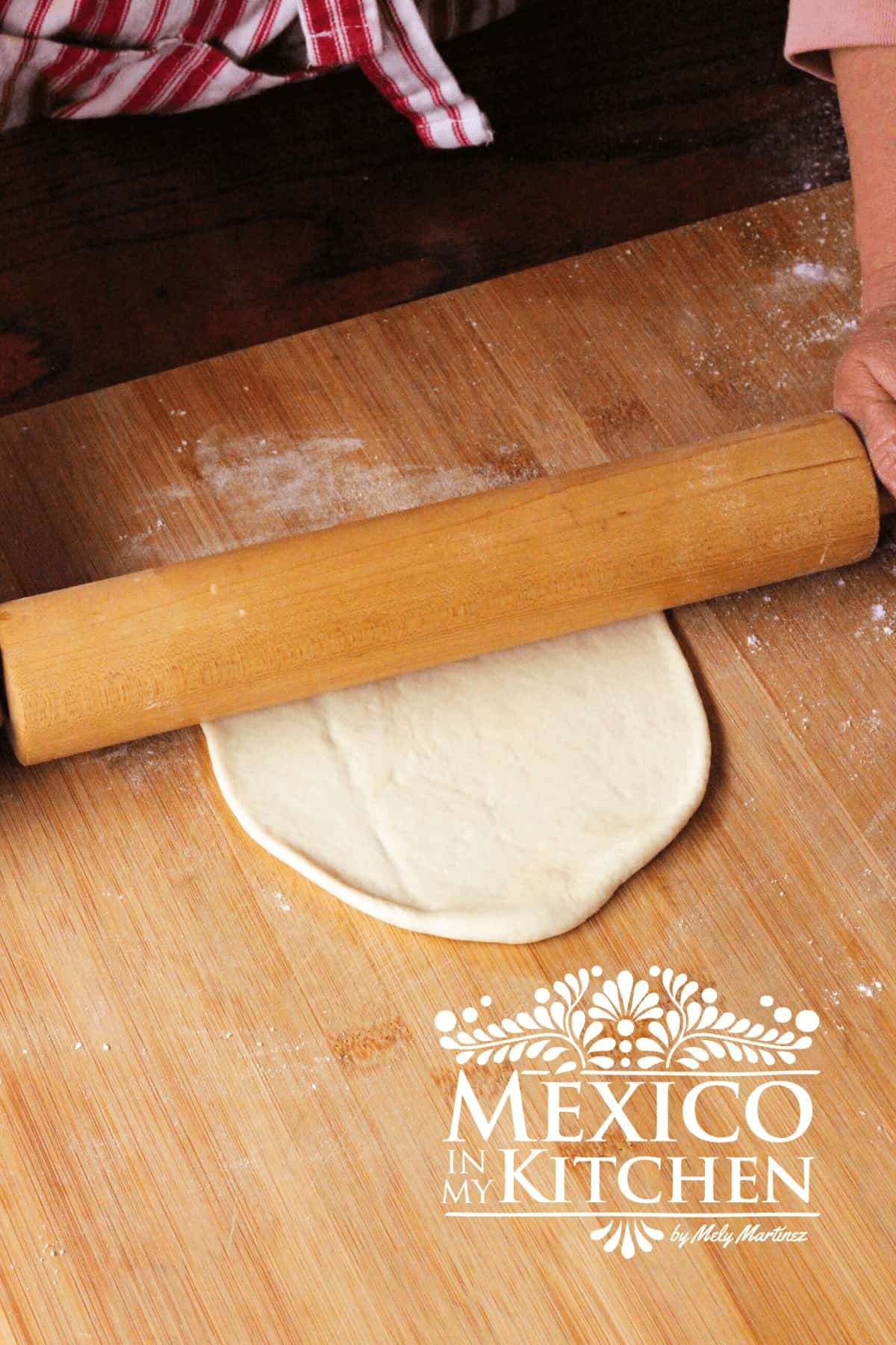 Rolling the dough with a rolling pin over a floured surface.