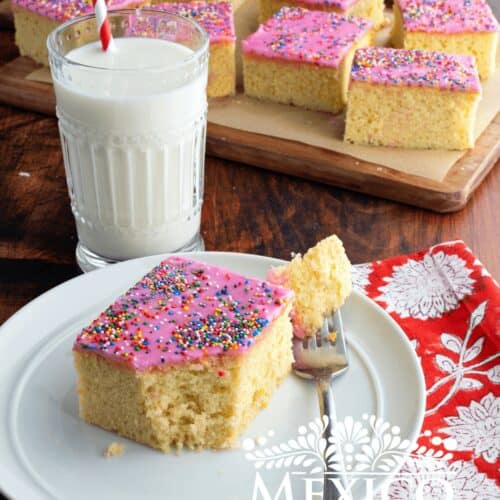 Cortadillo, Mexican pink cake slice on a plate, next to a cup of milk.