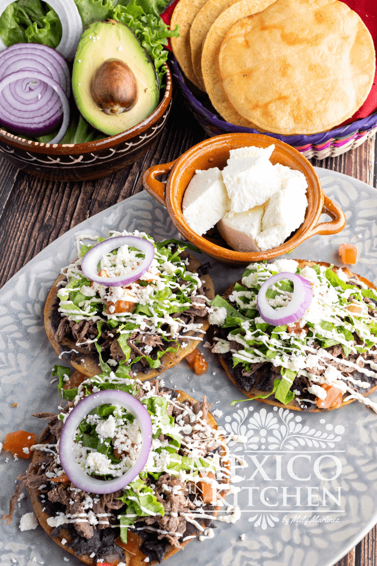 Beef tostada with toppings like beans, lettuce, Mexican crema , and queso fresco.