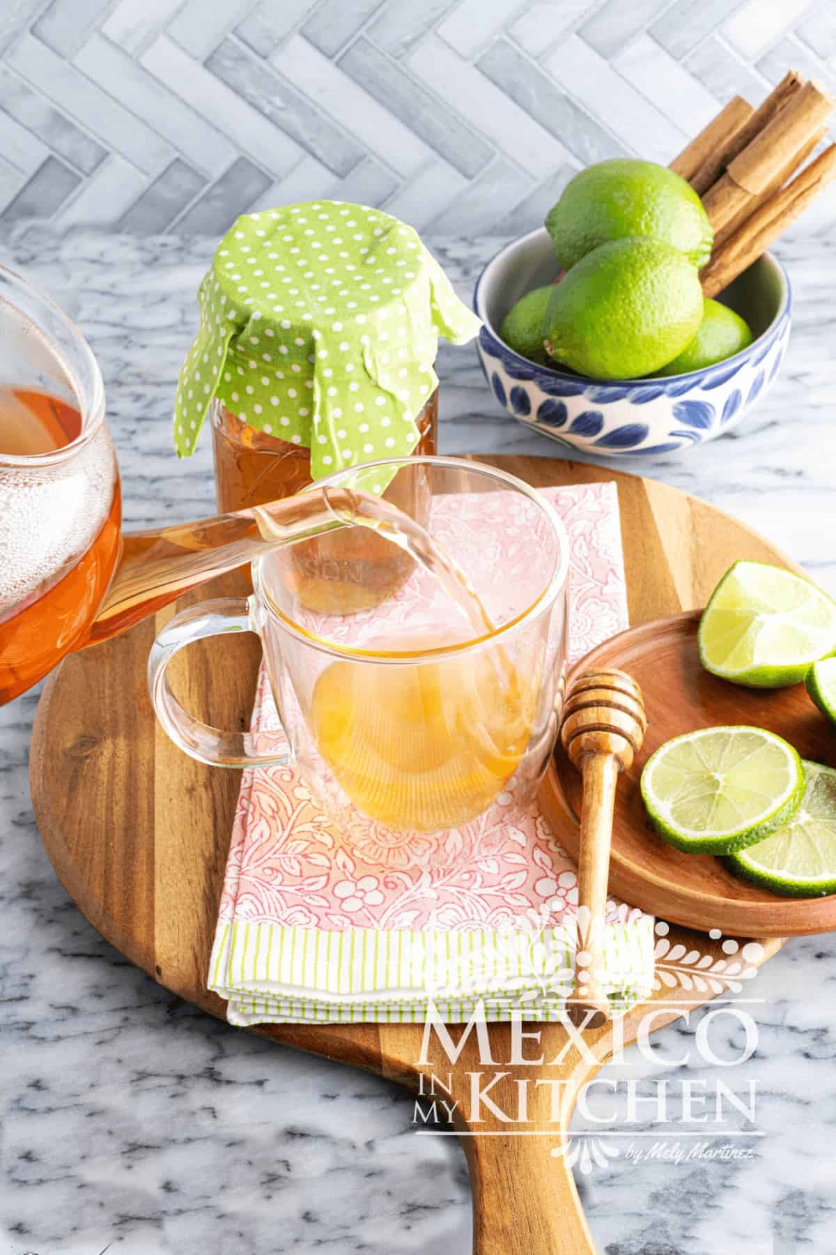 Hot tea served in a glass cup next to lime wedges