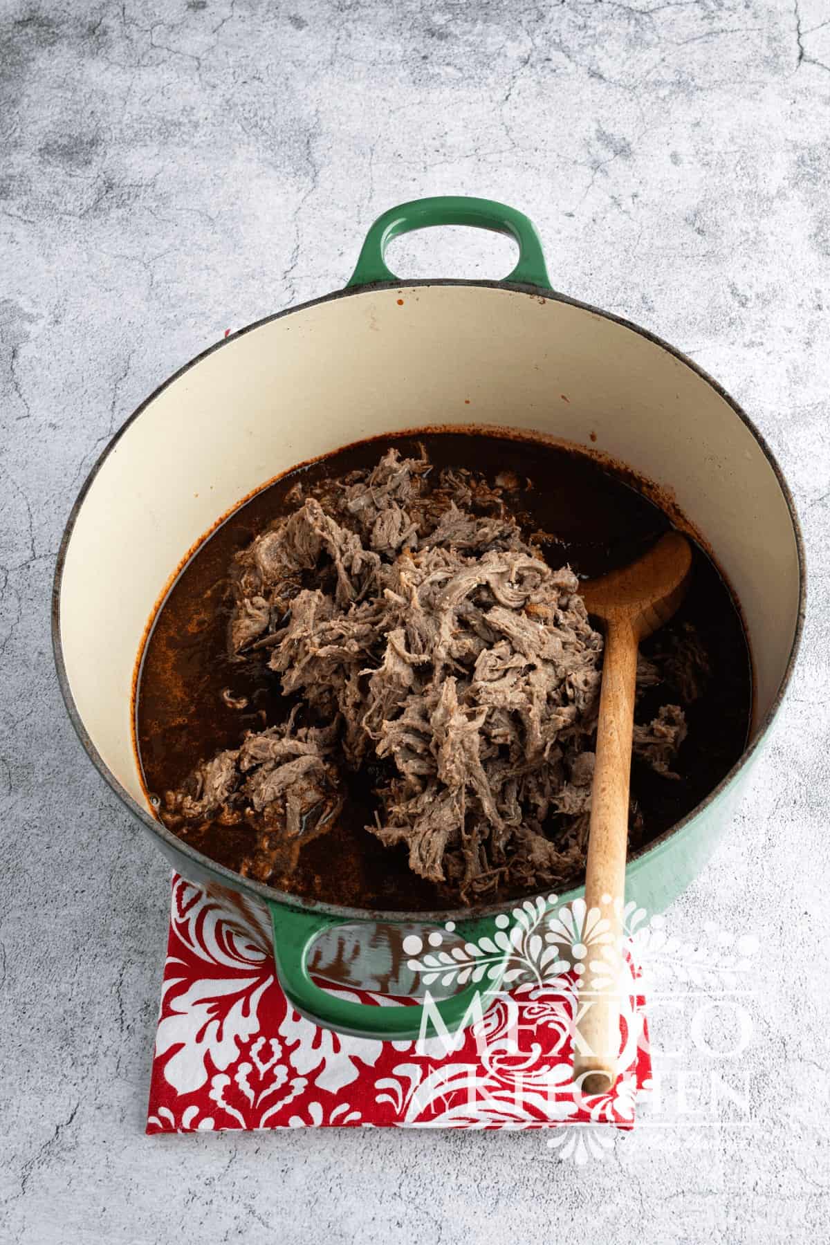 Shredded beef in a cast iron pot with sauce.