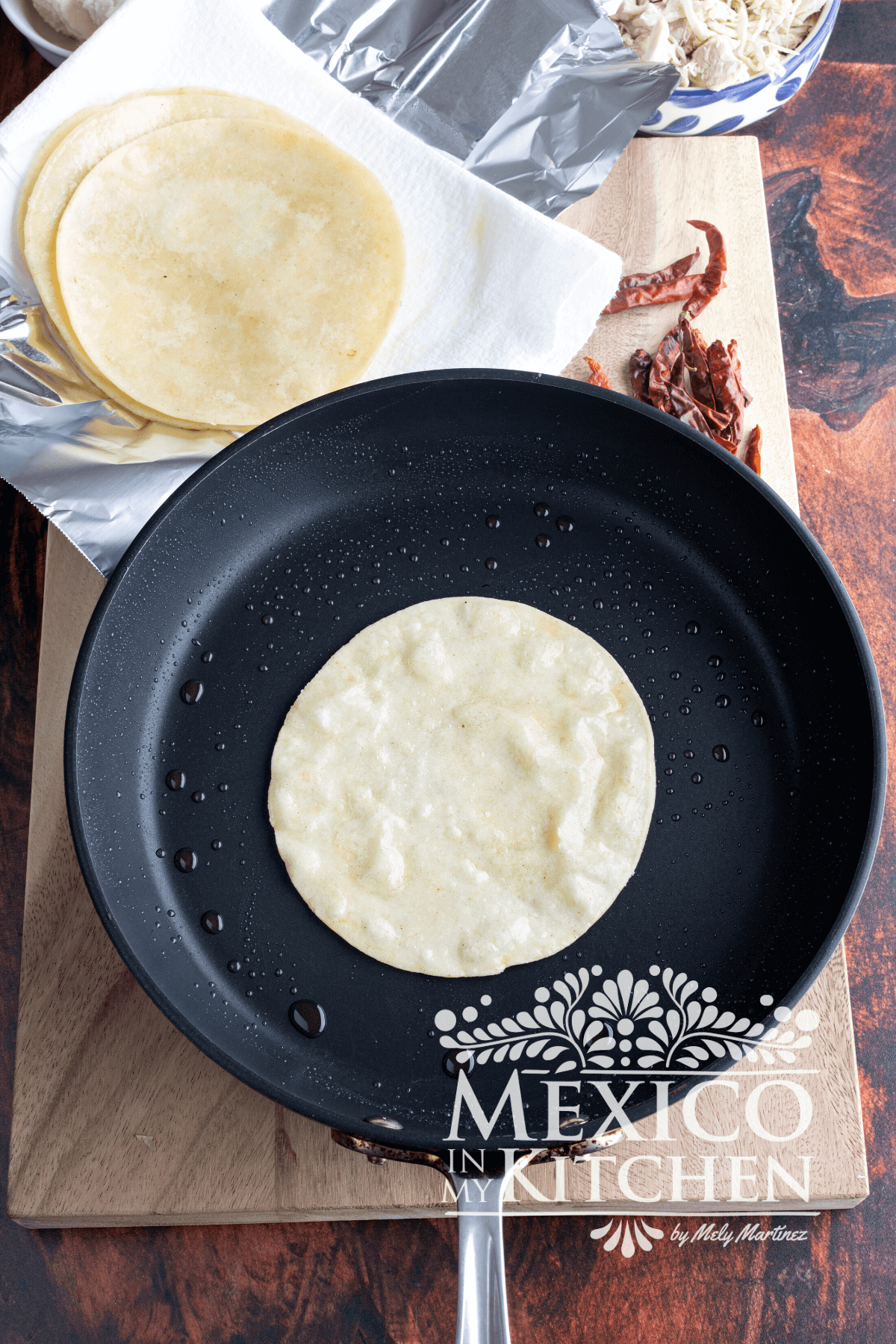 Slightly frying a corn tortilla in a frying pan with oil.