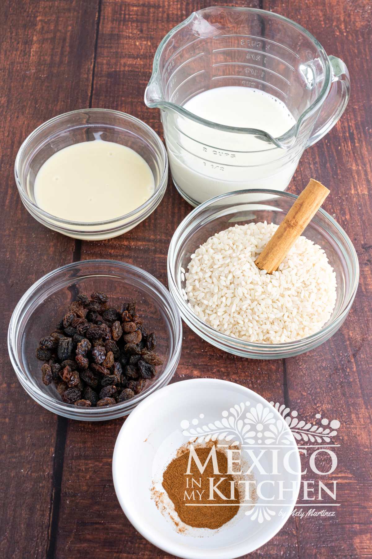Ingredients, like milk, sweetened condensed milk, raisins, and cinnamon displayed in a table.
