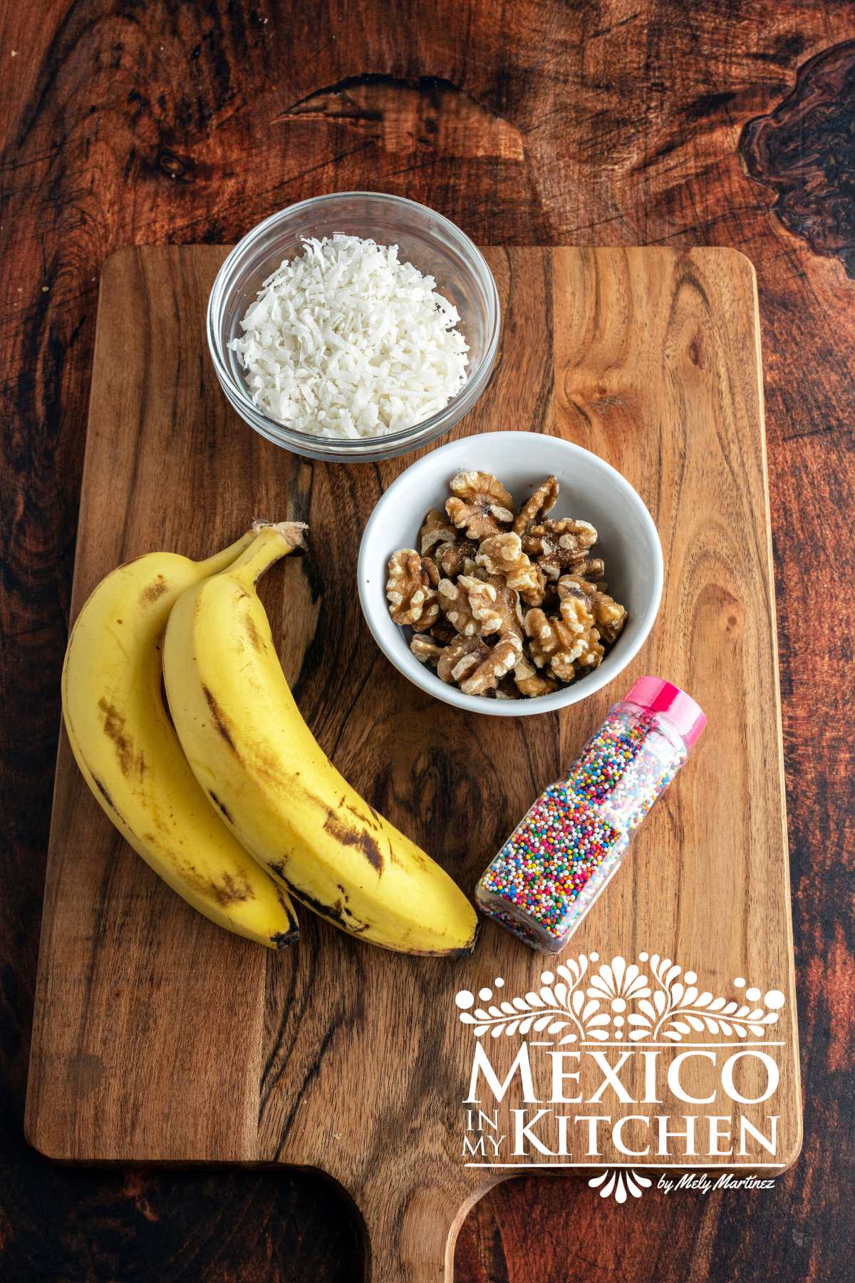 Bananas, walnuts, shredded coconut and color sprinkles on a cutting board.