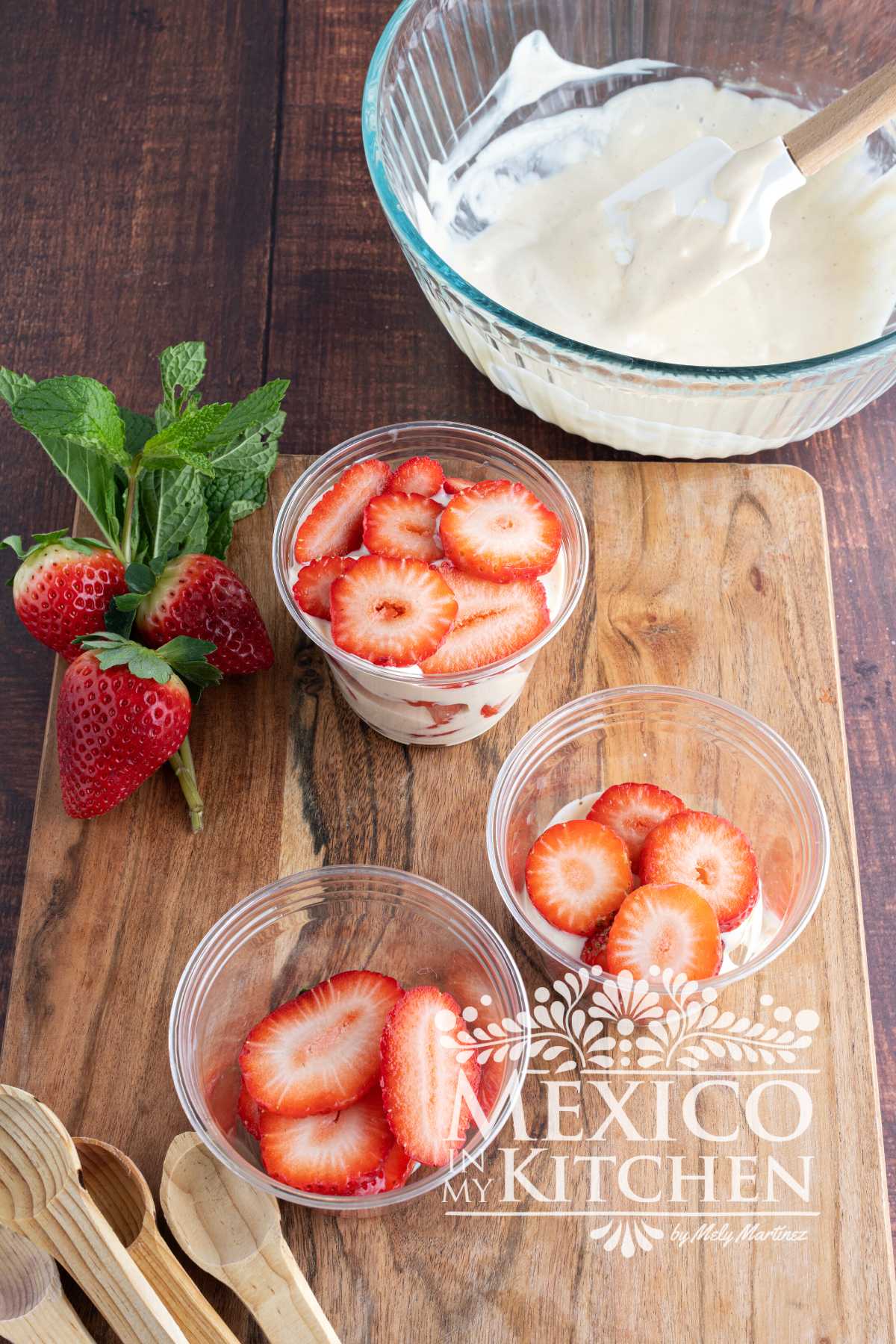 Filling plastic cups with cream mixtures and strawberries.