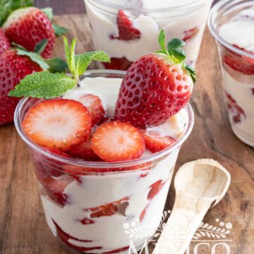 Fresas con crema in a plastic cup, garnished with a sprig of fresh mint.
