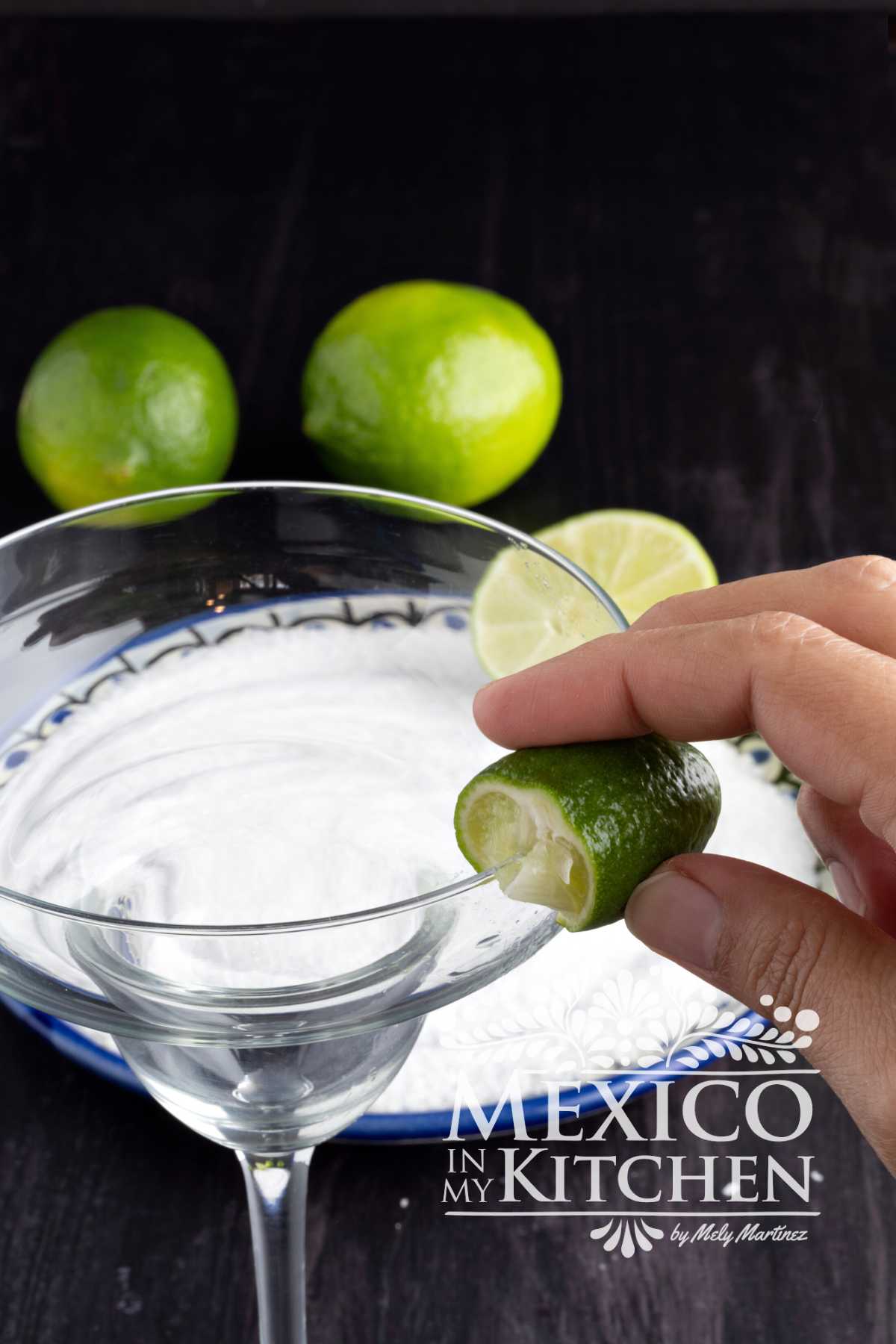 Rubbing a lime wedge over the margarita rim.