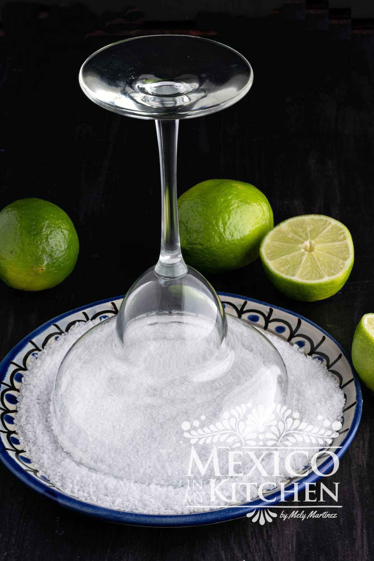 Upside-down cocktail glass over a plate of kosher salt.
