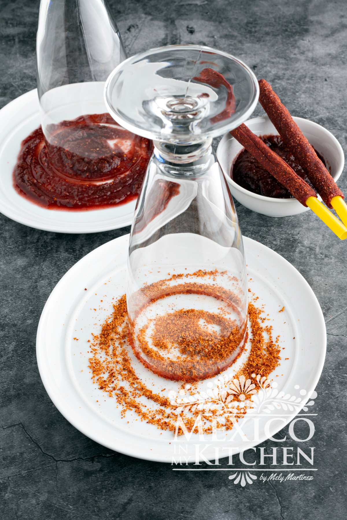 Preparing the rim of a tall glass with Chamoy Sauce and tajin powder.