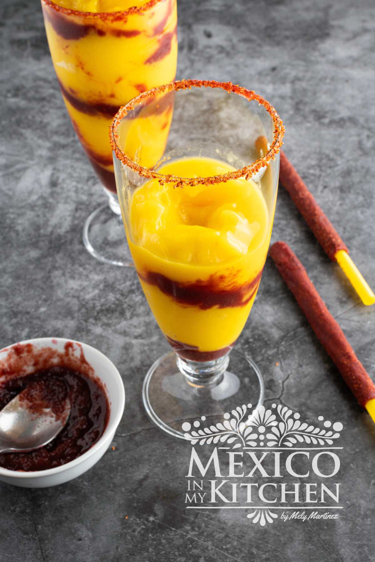 Mixing mango mixture with Chamoy Sauce in a tall glass.