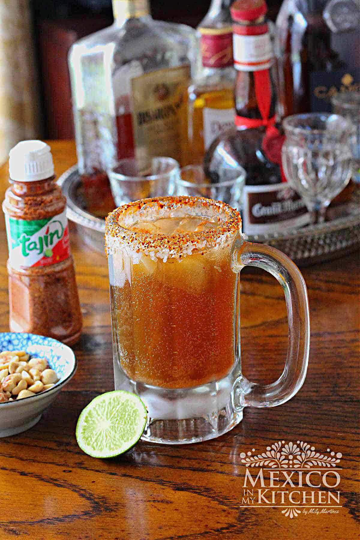 Michelada cocktail served in a frozen glass, next to a wedge of lime and cocktail peanuts.