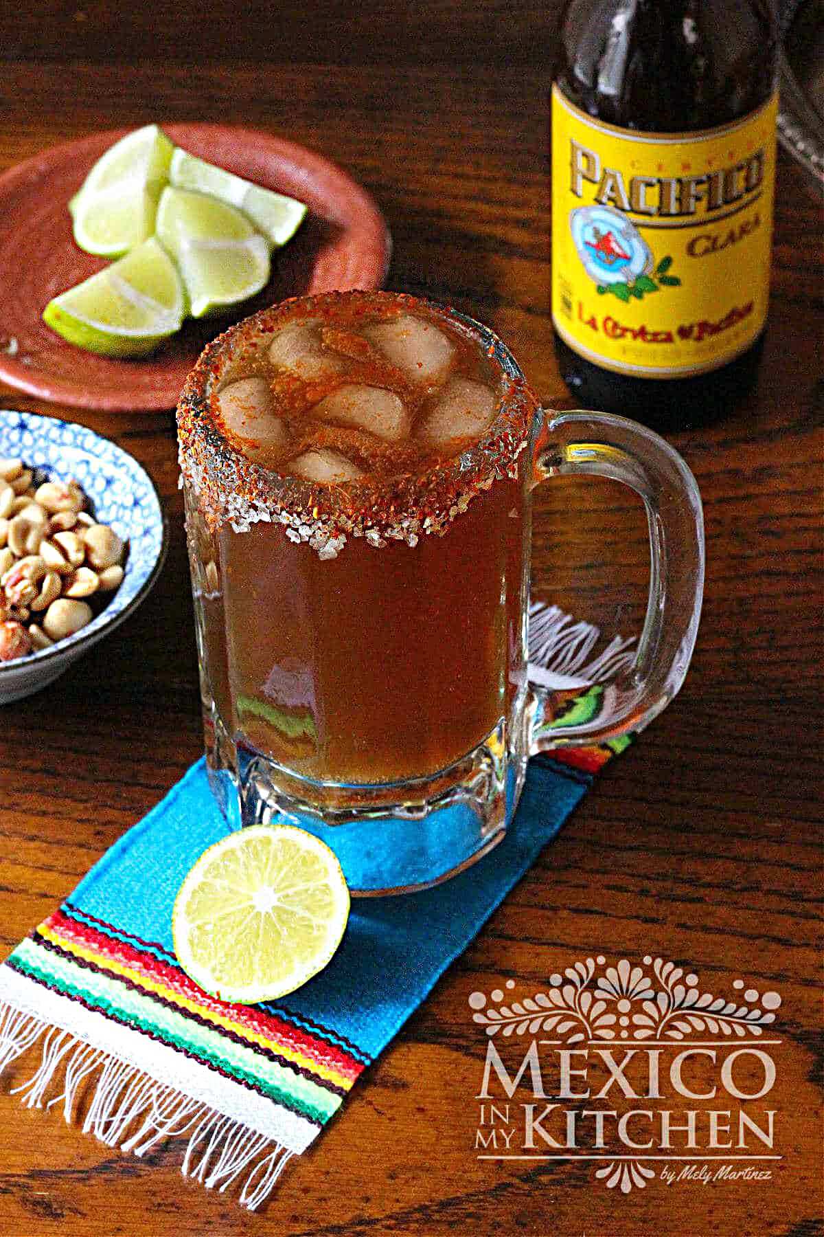 Michelada cocktail served in a frozen glass, next to a wedge of lime and beer.