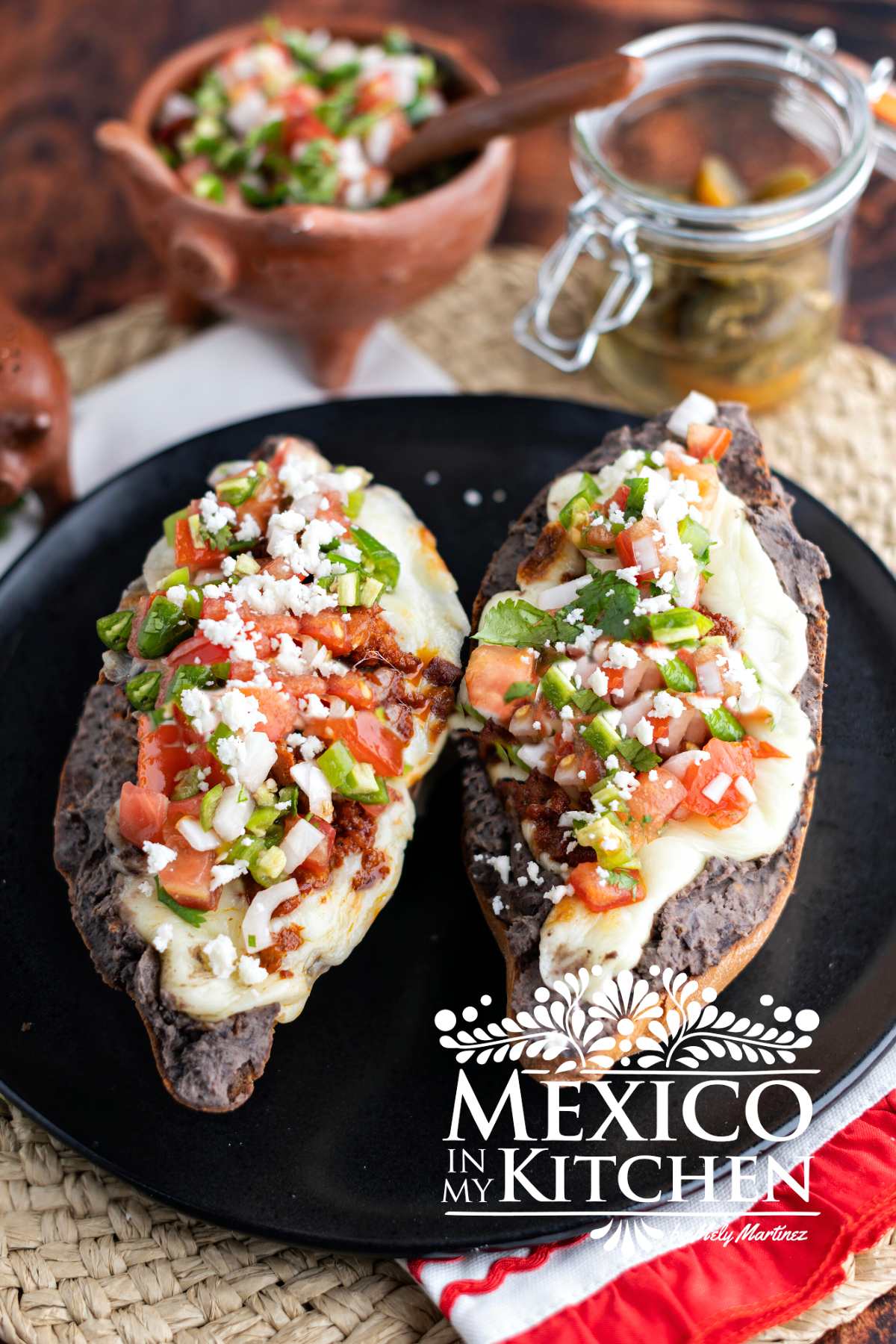 Mexican molletes topped with pico de Gallo on a plate.