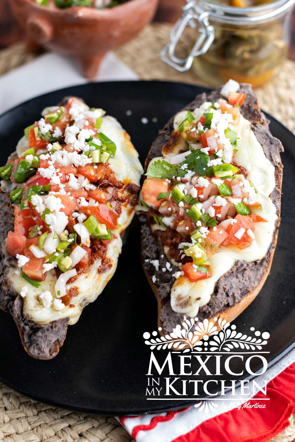 Mexican molletes topped with pico de Gallo on a plate.