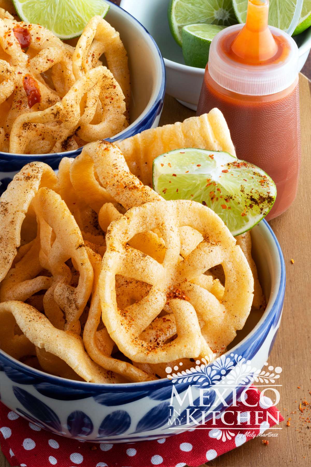 Chicharrones de harina is served in a bowl topped with chili powder and lime.