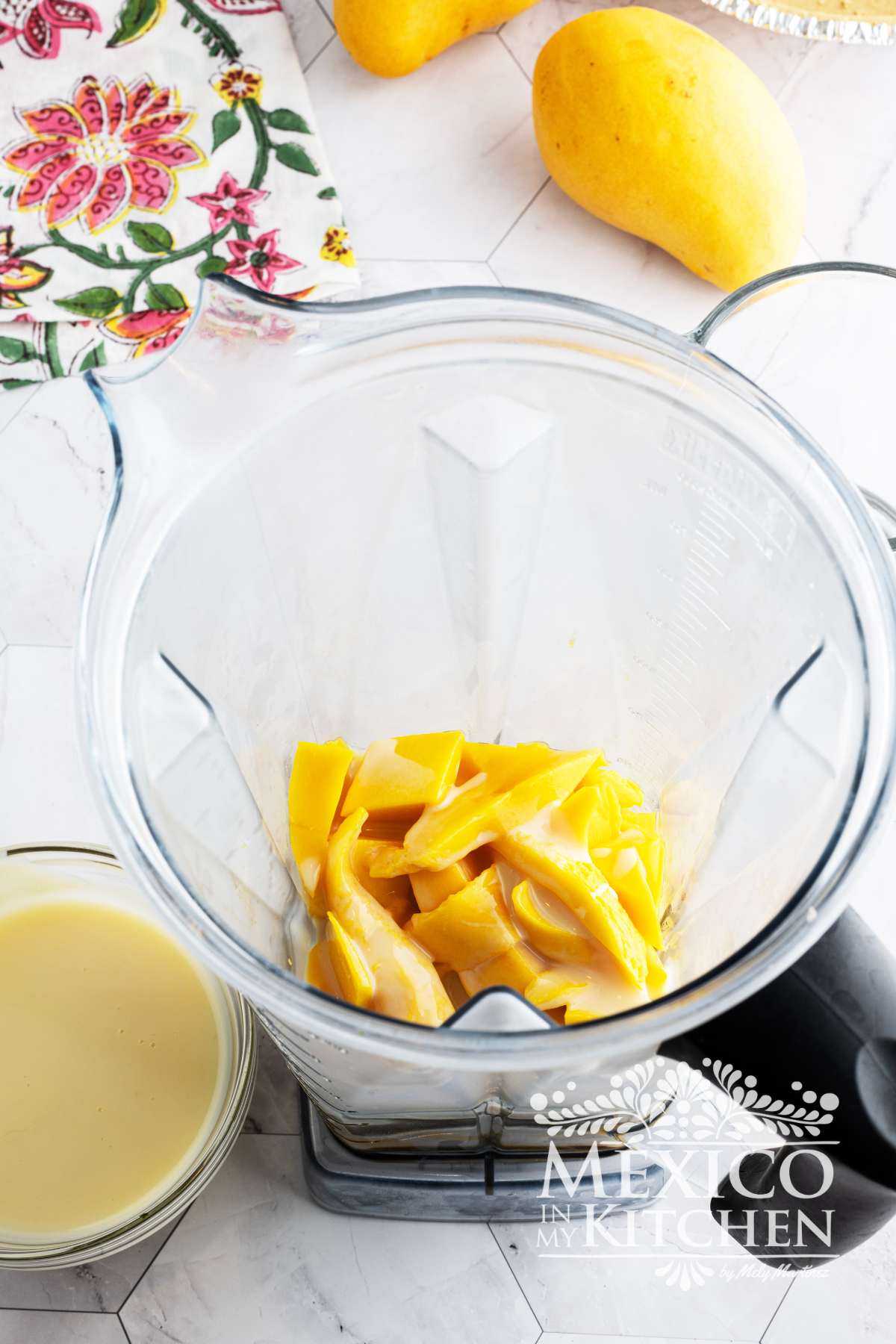Mango chunks in a blender with condensed milk.