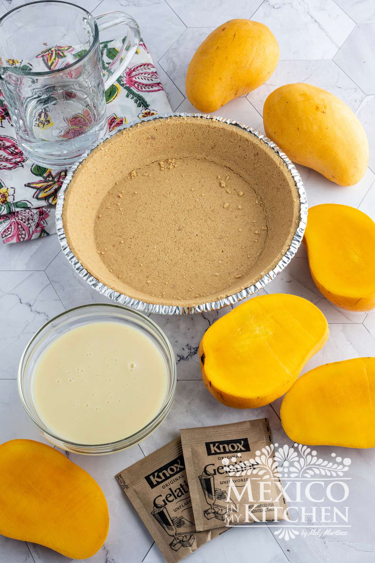 Fresh mango, next to condensed milk, store bought pie crust and gelatin powder.