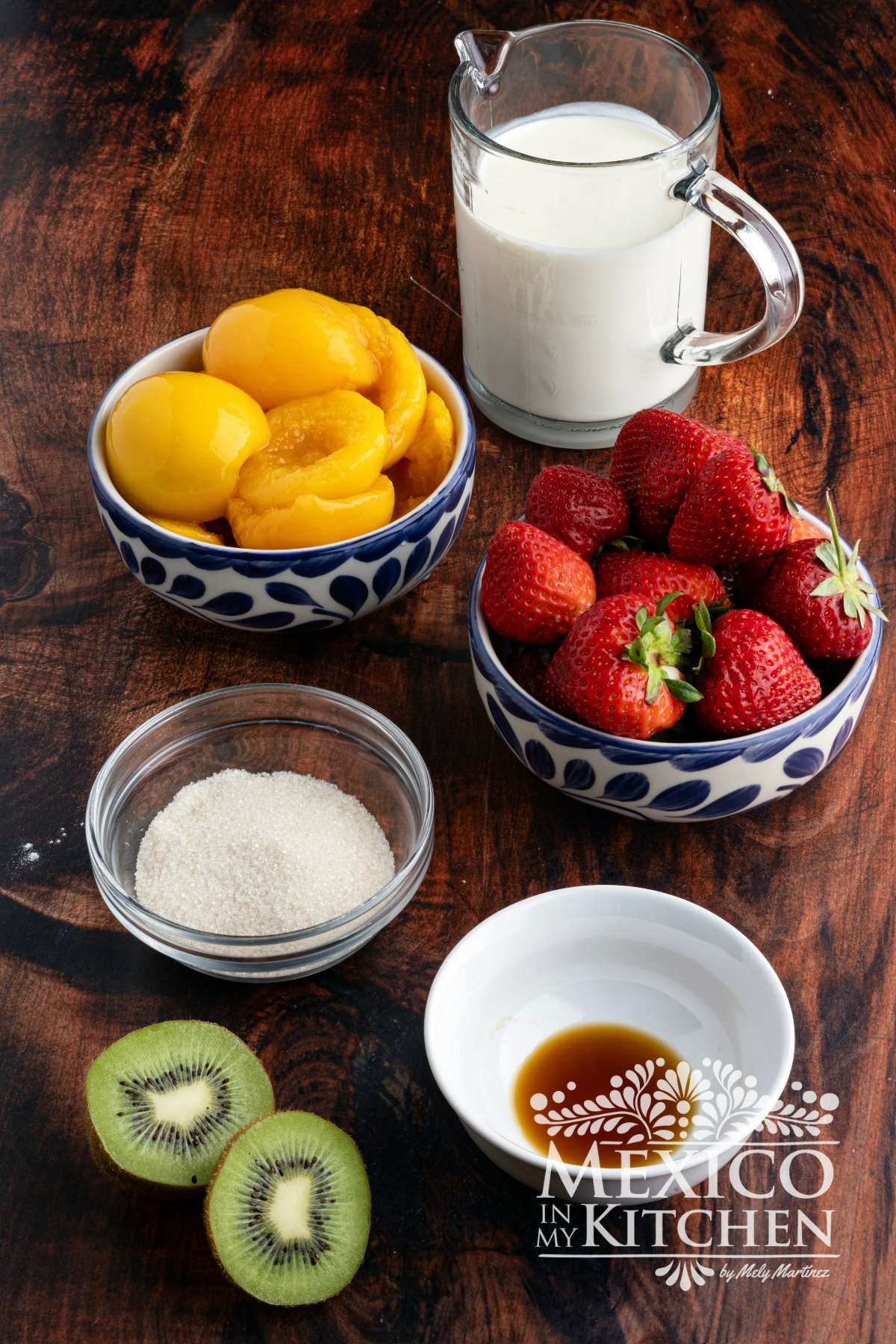Heavy whipping cream, fresh strawberries, peaches, sugar and kiwis on a table.