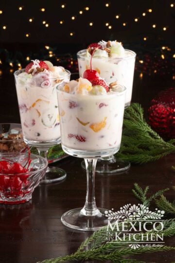 Ensalada de fruta Navideña (Mexican Christmas Salad) served in a wine glass, topped with a maraschino cherry.