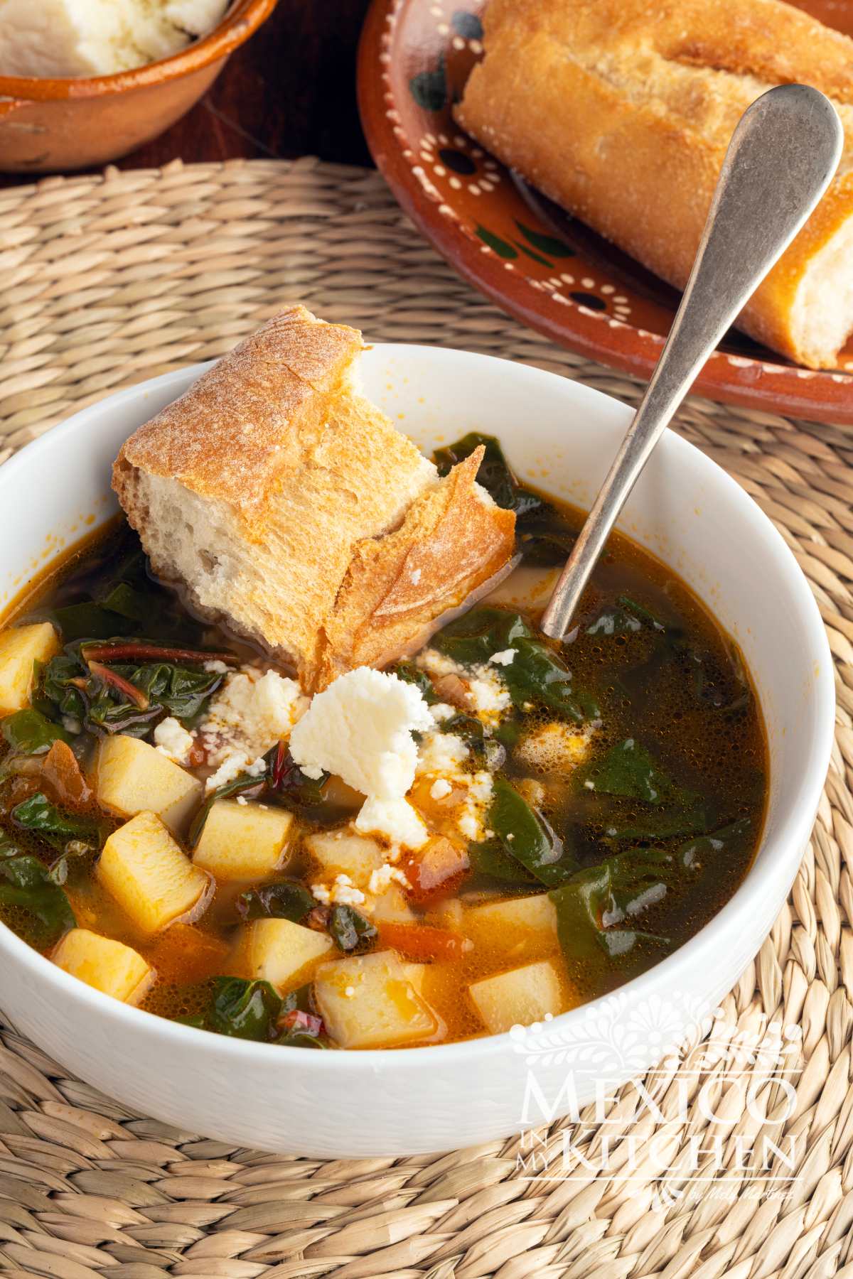 Swiss Chard and Potato Soup | Sopa de Acelgas con Papas served in a bowl next to a crusty roll.