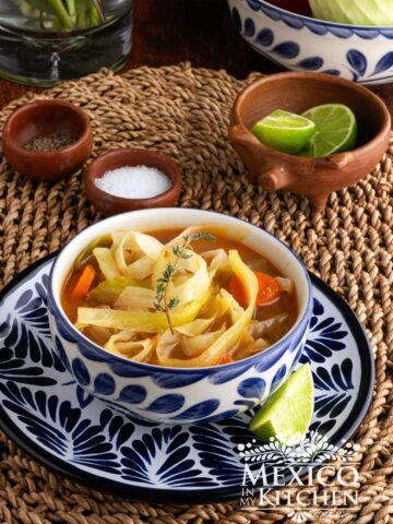 A bowl of cabbage soup, topped with a fresh thyme.