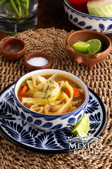 A bowl of cabbage soup, topped with a fresh thyme.