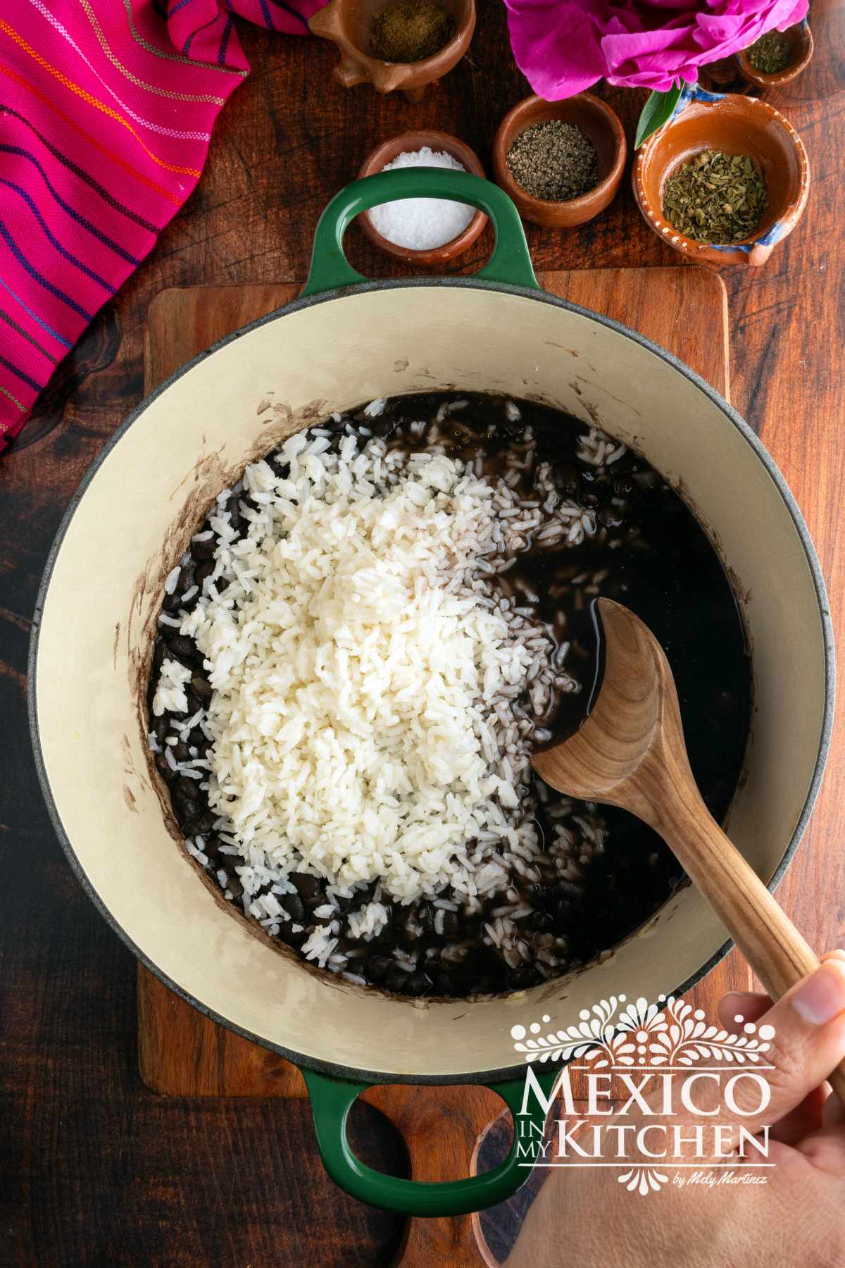 Cooking sautéed chopped onions and garlic with black beans, and rice in a cast iron pot.