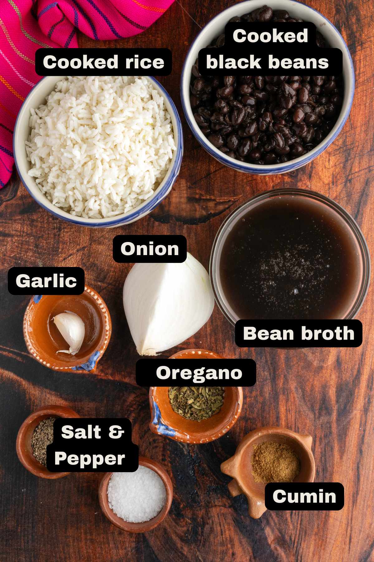 Ingredients in a table such as cooked beans, bean broth, cooked rice, onion, garlic, Mexican oregano, cumin, and salt and pepper.